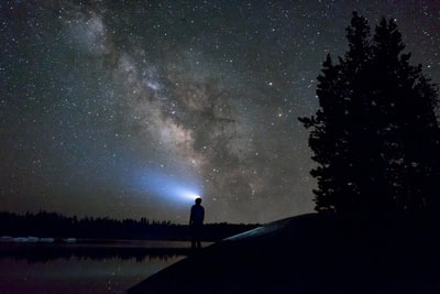 轮廓的男人站在夜空下的水域
